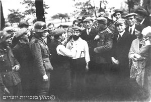 חיילים גרמנים מאלצים יהודי לגלח זקן של יהודי אחר לעיני אוכלוסייה מקומית בוורשה בסתיו 1939