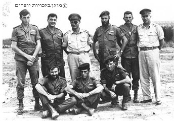 הרמטכ"ל משה דיין (עומד, רביעי מימין) בחברת לוחמי יחידה 101 והצנחנים, 28 באוקטובר 1955